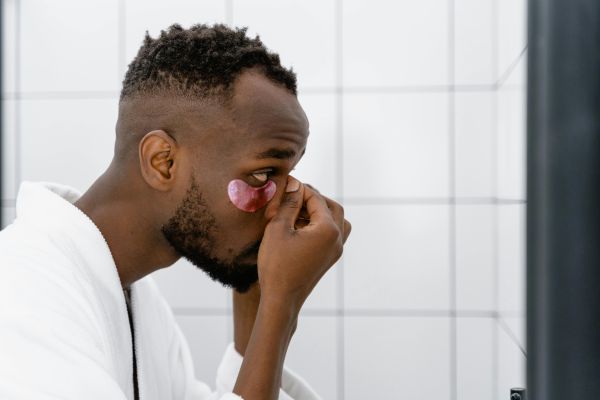 A Side View of a Man Putting an Under Eye Mask on His Face