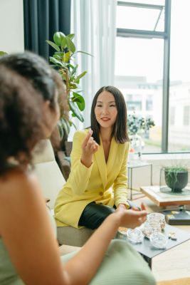 Asian nutritionist in a yellow blazer advising a client on healthy supplements indoors.