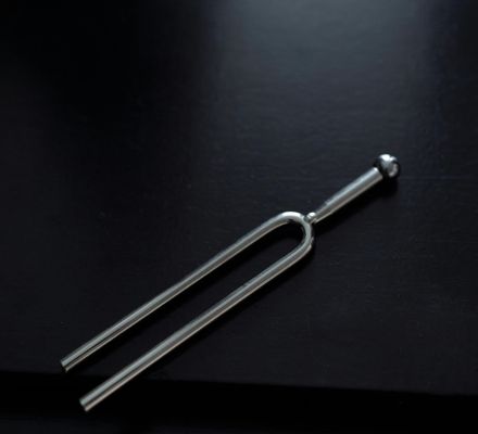 Close-up of a tuning fork on a sleek black surface with copy space.