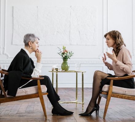 Two women engaged in a counseling session in a bright, modern loft setting.